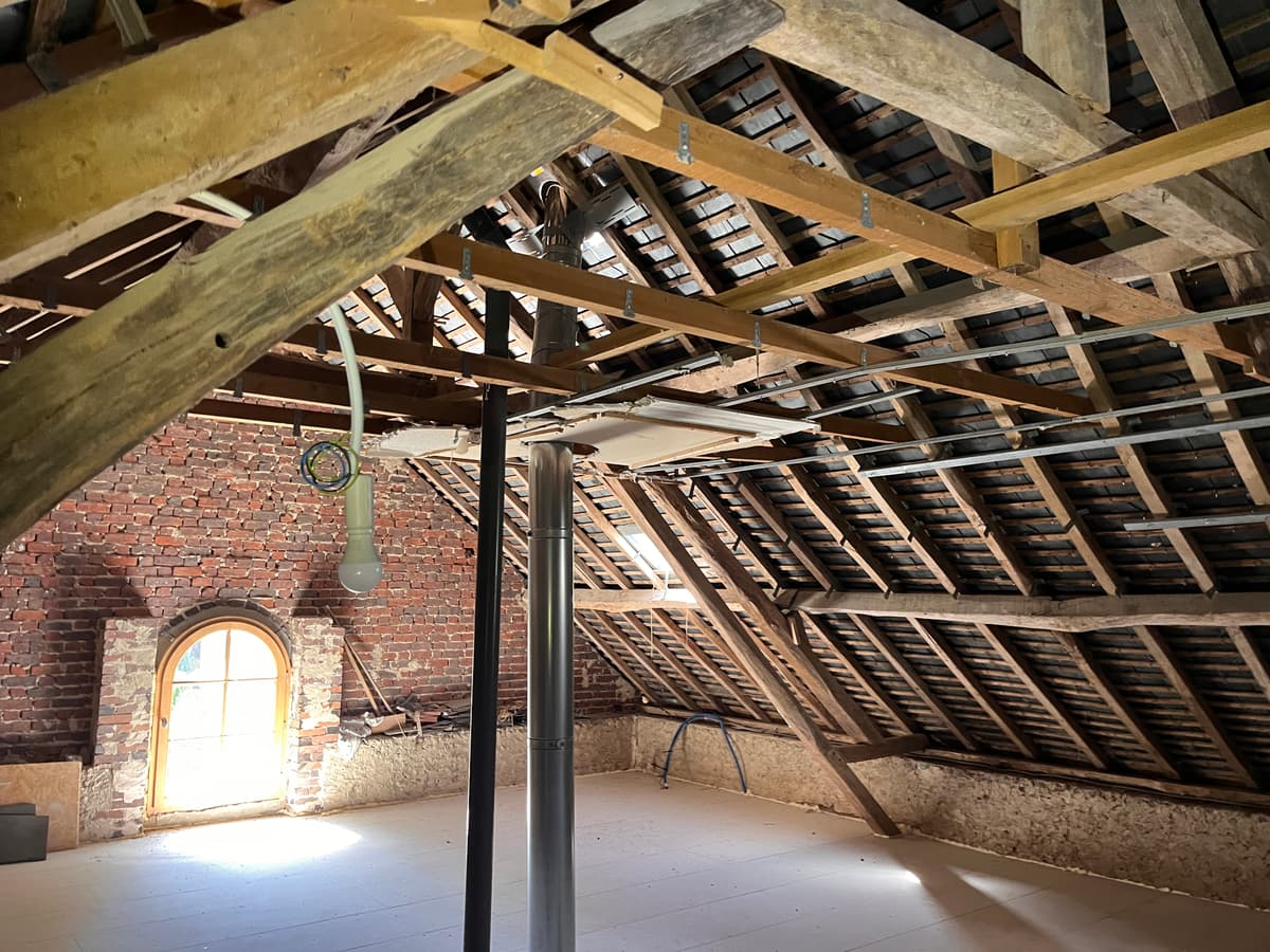 Grand comble en charpente traditionnelle avec poteaux metalliques de renfort et fenetre cintree