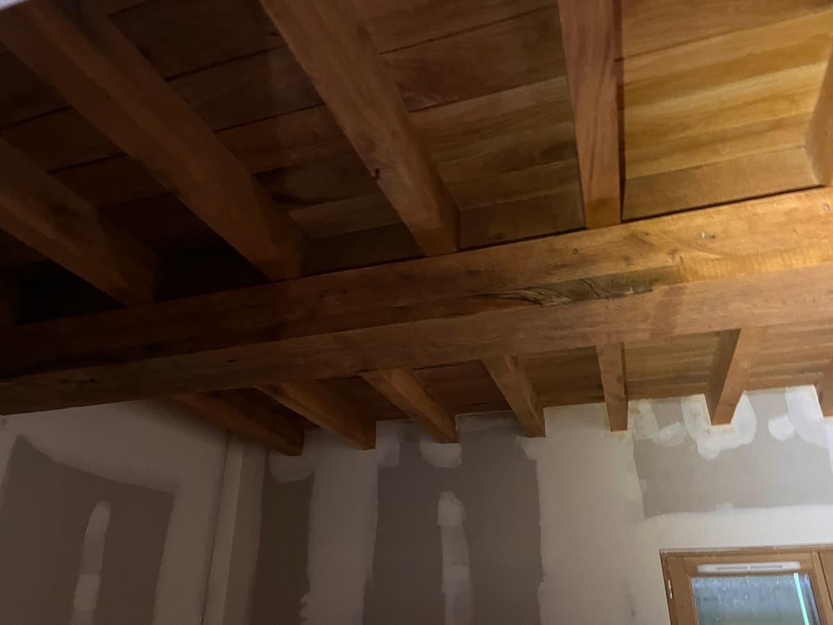 Plafond a solives en chene clair au-dessus de murs enduits